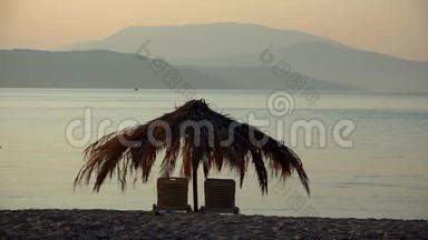 海滩上的躺椅和棕榈树伞，在异国<strong>度假</strong>胜地放松<strong>度假</strong>，带海和山的彩色日落